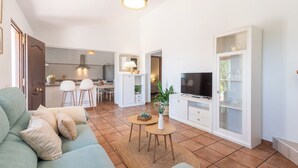 Un salon moderne avec un canapé, un téléviseur et un coin repas comprenant des chaises et une table.