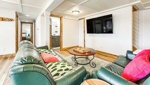 Uma sala de estar moderna com um sofá longo de couro verde, uma mesa de centro e uma televisão de tela plana na parede.