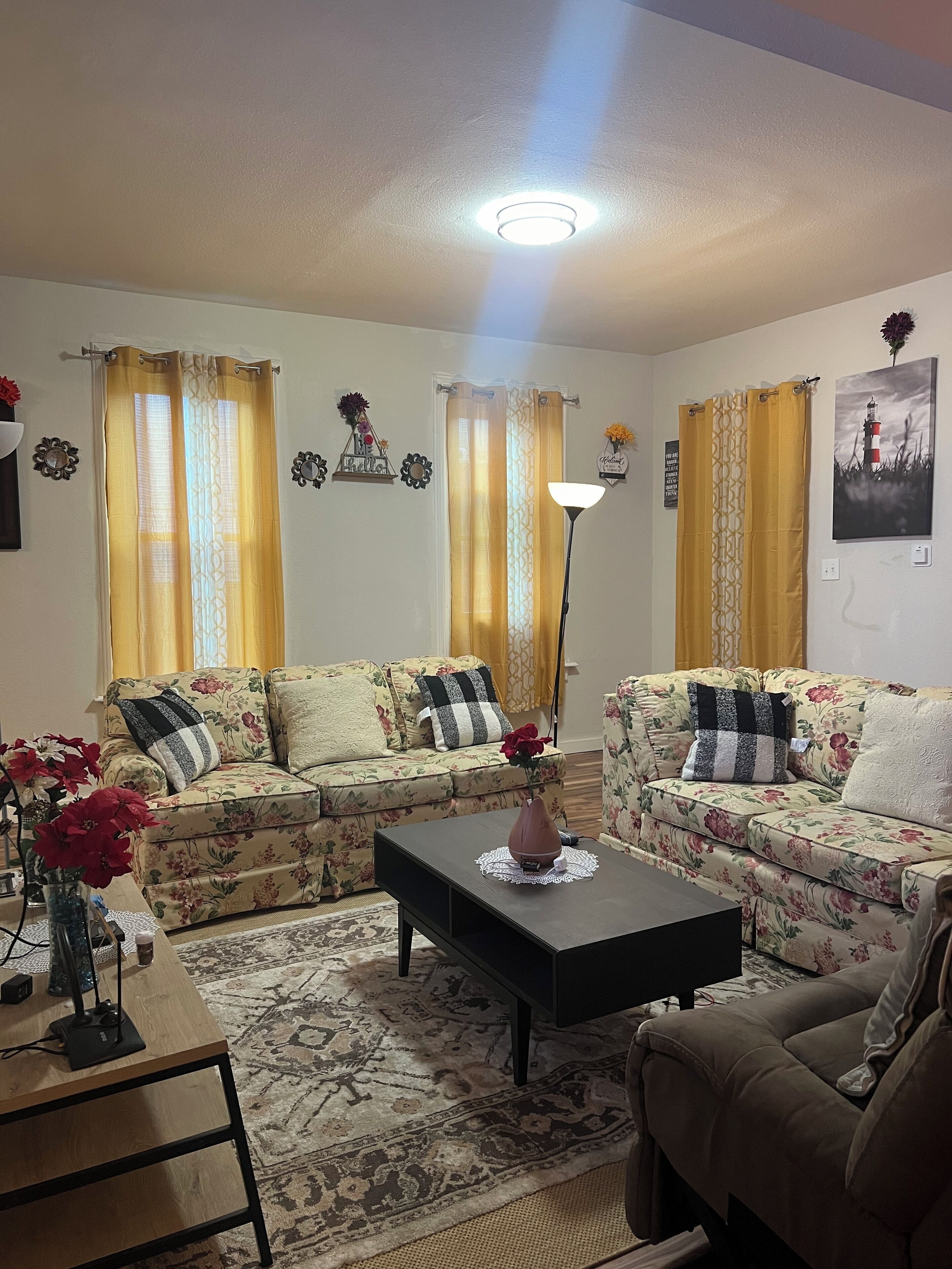 Un salon avec deux canapés à motifs floraux, une table basse et une lampe.