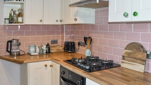 Una cucina con un piano cottura a gas, una macchina per il caffè, un tostapane e un tagliere in legno.