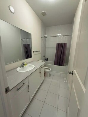 A modern bathroom with a sink, mirror, toilet, and shower. - Ajax Villa  (Ajax)