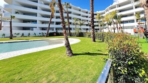 Un hôtel moderne doté de nombreux balcons blancs, d’une piscine et d’un espace vert bien entretenu.