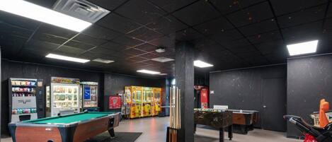 A recreational room with pool tables, foosball, and arcade games.