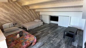 A bedroom with a bed, a bedside table, a TV, and built-in storage cabinets. - Relax by the Sea – Cozy 2-Bedroom Apartment with Terrace in Campomarino lido (Campomarino)