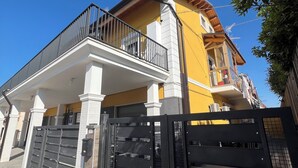 A two-story house with a balcony, a gated entrance, and a clear blue sky. - Relax by the Sea – Cozy 2-Bedroom Apartment with Terrace in Campomarino lido (Campomarino)