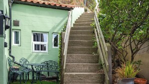 A set of stone steps leading up to a green-painted house with a small garden area, including a table and chairs. - 2 bedroom accommodation in Staithes (Staithes)