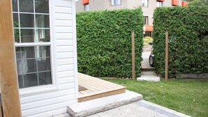 A house with a white exterior, a wooden deck, and a well-maintained hedge. - The Little Lake House-Cozy 2Bdrm (Midland)