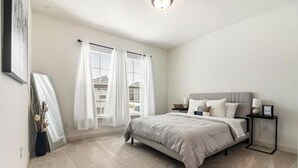 Un dormitorio con cama, mesitas de noche y una ventana con cortinas.