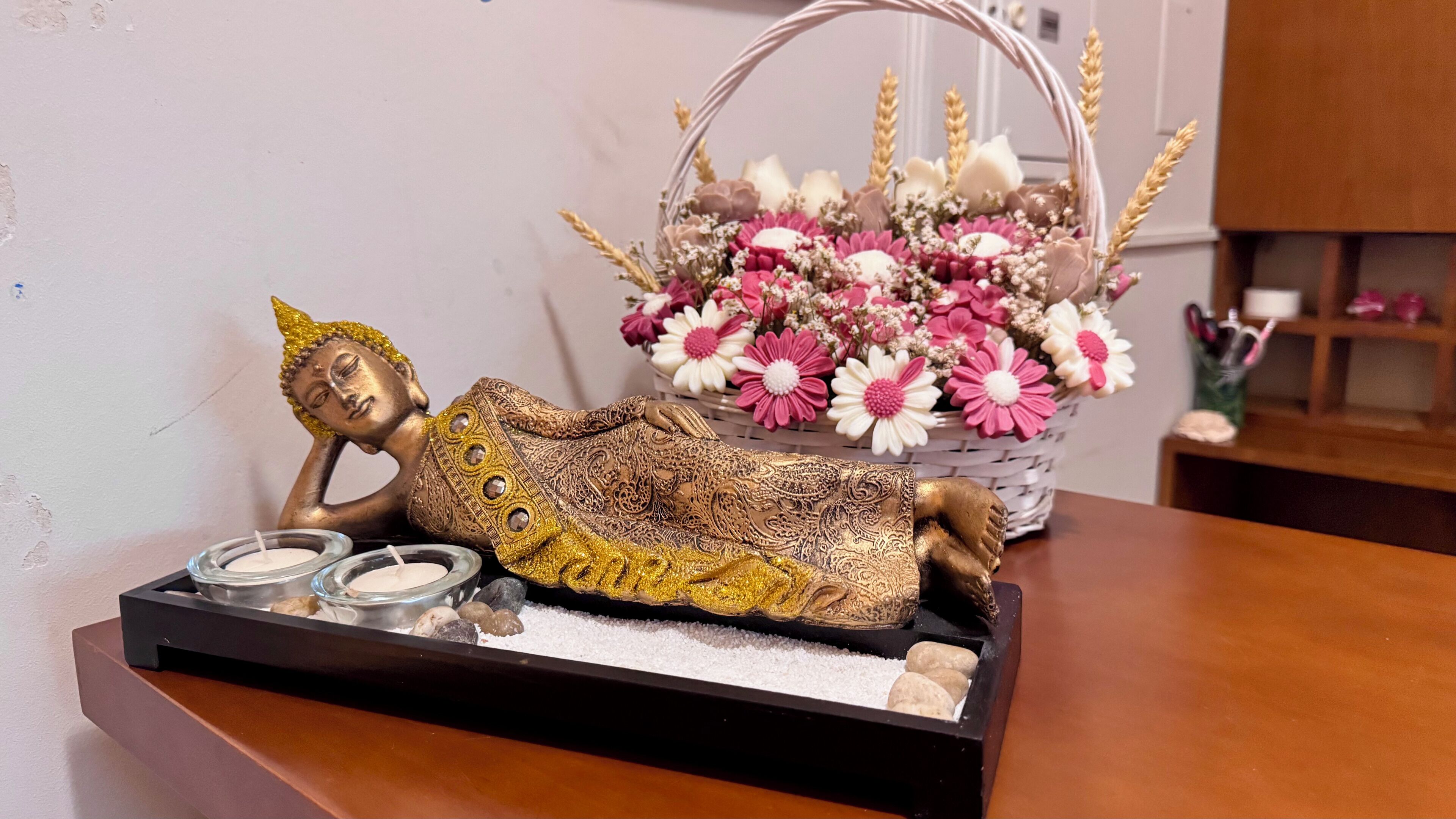 Una estatua de una figura reclinada con diseños intrincados, un candelabro con velas y una cesta de flores.