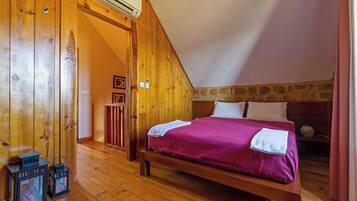 A bedroom with a wooden bed, a stone wall, and a wooden door.