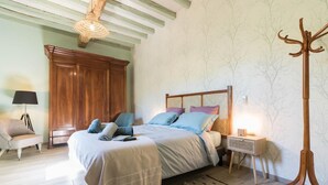A bedroom with a bed, bedside table, lamp, and coat rack. - La Ralle - DONNEVILLE (DONNEVILLE)