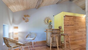 A room with wooden flooring, a wicker chair, a small table with a vase, and a wall with a wooden panel. - La Ralle - DONNEVILLE (DONNEVILLE)