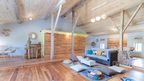 A spacious living room with wooden floors, a sofa, and a dining area with a table and chairs. - La Ralle - DONNEVILLE (DONNEVILLE)