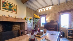 A rustic kitchen with a brick wall, a wooden table, and a vase with sunflowers. - La Ralle - DONNEVILLE (DONNEVILLE)