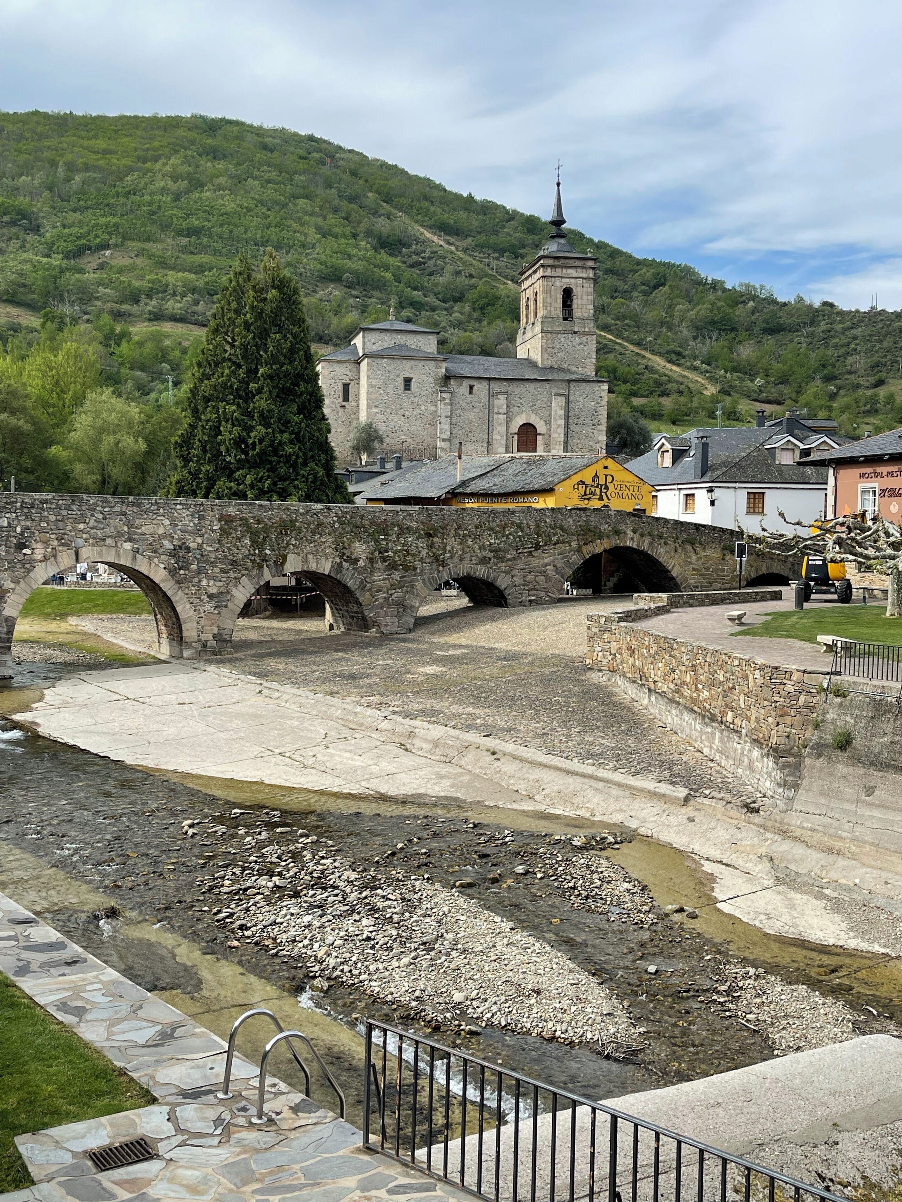 Eine Steinbrücke über einem Fluss, im Hintergrund eine Kirche und Gebäude.