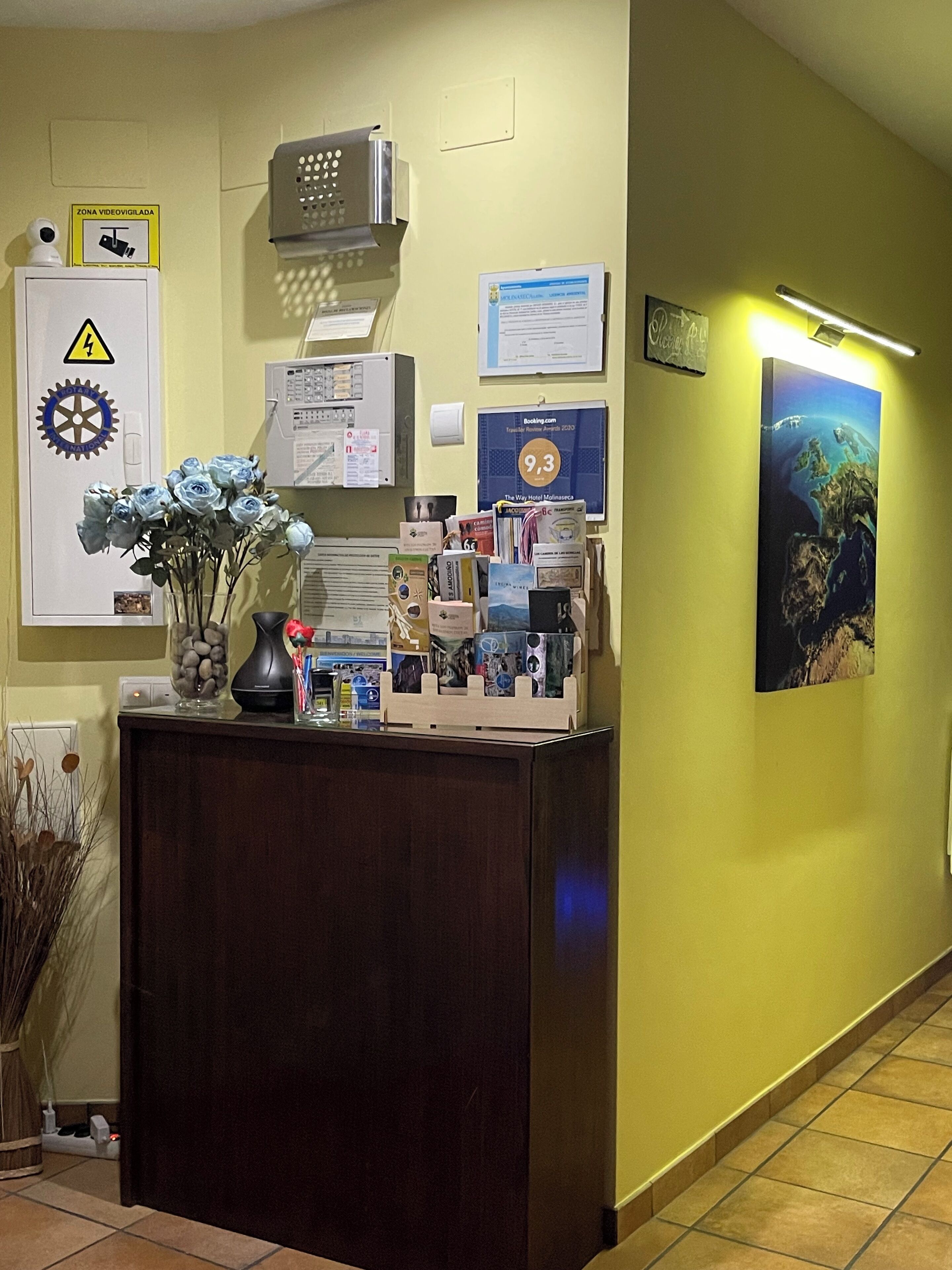 A reception desk with a vase of flowers, a clock, and various informational posters on the wall.