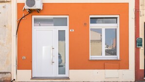 A building with an orange facade, a white door, and a window. - La casa di Amelie - Cabras (Cabras)