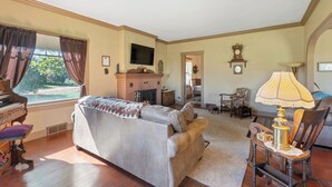 Una sala de estar con un piano, un sofá, un televisor y una chimenea.