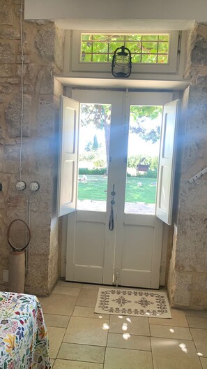 A room with a double door leading outside, a small window above the door, and a tennis racket hanging on the wall. - Richiami di Sicilia (Modica)