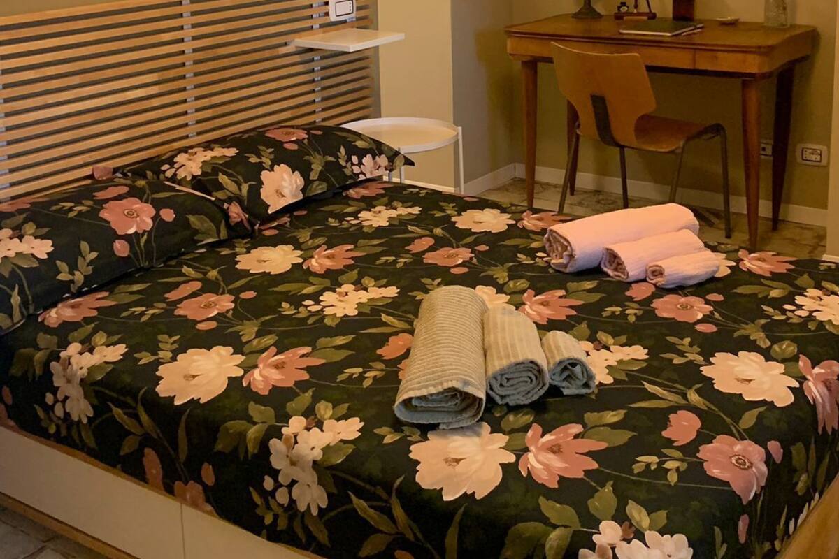 A bedroom with a bed, a desk, and a chair.