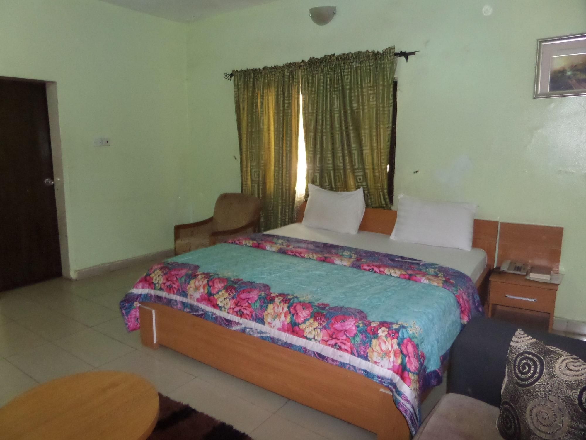 A bedroom with a bed, a chair, a nightstand, and a small table.