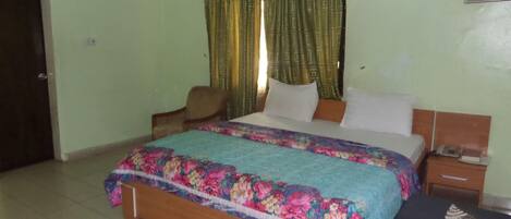 A bedroom with a bed, a chair, a nightstand, and a small table.