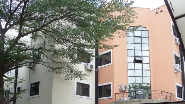 A multi-story building with a flat facade, air conditioning units, and a balcony with decorative railings. - Golden Astoria Hotel (Abuja)