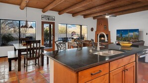 A spacious kitchen with a large island, wooden ceiling beams, and a view of the desert through large windows. - Sonoran gem in Hidden Valley with POOL! (Tucson)