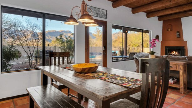 A dining area with a wooden table, benches, and a large window with a view of mountains. - Sonoran gem in Hidden Valley with POOL! (Tucson)