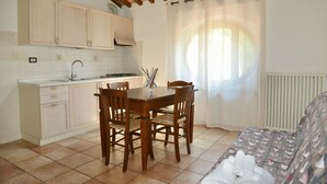 A compact kitchen with wooden cabinets, a dining table with chairs, and a sofa with a patterned cover.