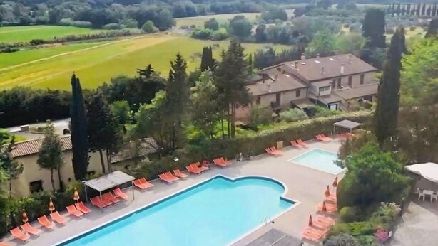 A pool area with lounge chairs and a building in the background.