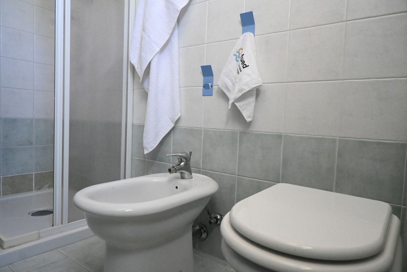 A bathroom with a bidet, a toilet, and a shower area.