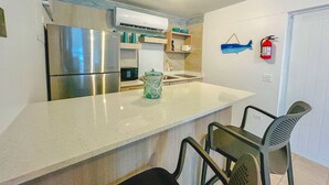 Una cocina moderna con electrodomésticos de acero inoxidable, una encimera blanca y un pequeño comedor con dos sillas.