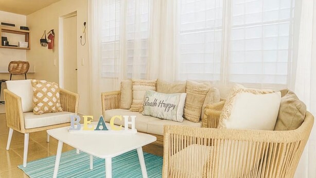 Una sala de estar acogedora con un sofá, dos sillones, una mesa baja y una alfombra.
