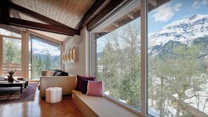 Ein modernes Wohnzimmer mit großem Fenster mit Blick auf eine verschneite Berglandschaft.