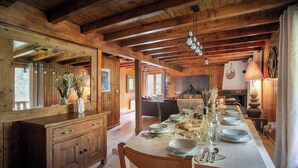 A wooden interior with a long dining table set for a meal, a wooden cabinet, and a mirror. - Chalet Rochamour - mountain holiday for 14 with spa - OVO Network (Châtel)
