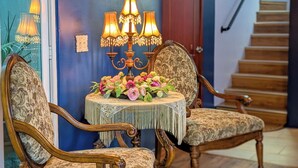 Une pièce comprenant deux fauteuils richement décorés, un lustre et un arrangement floral placé sur une petite table.