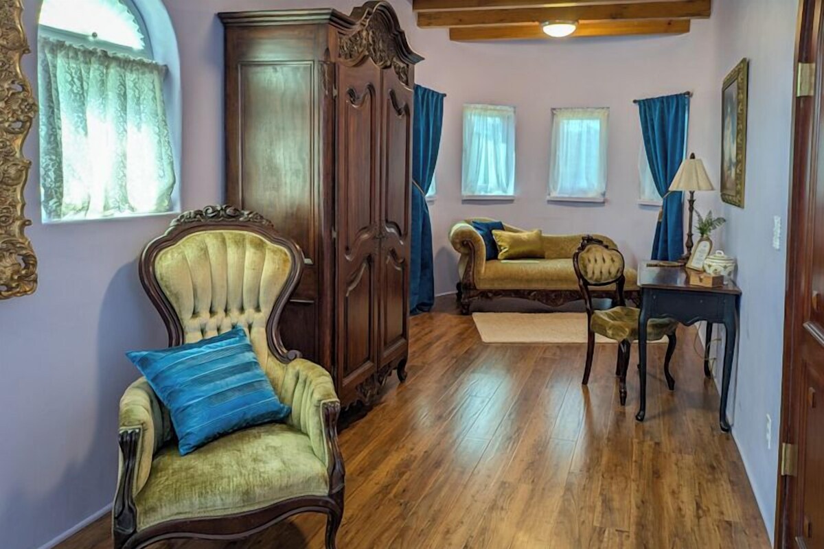 Une pièce avec un plancher en bois, une grande armoire, un canapé et un fauteuil avec un coussin.
