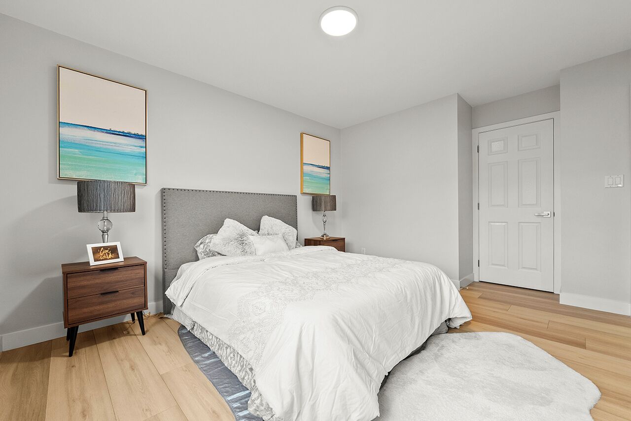 Een slaapkamer met een bed, nachtkastjes, een spiegel en kunstwerken aan de muur.