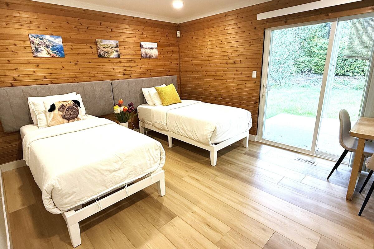 Une chambre avec deux lits, des murs en bois et une grande fenêtre.