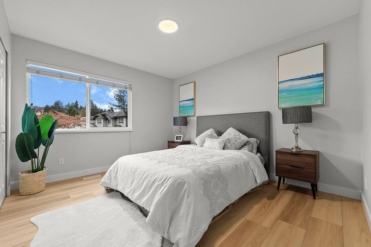Une chambre à coucher avec un grand lit, des tables de chevet, une plante en pot et une vue sur l’extérieur.