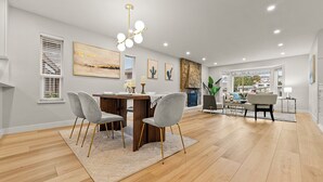 Un salon spacieux doté d’un plancher en bois, un coin repas avec une table et des chaises, et une cheminée.