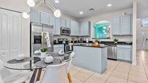 Une cuisine moderne avec des meubles de couleur bleu clair, des appareils en acier inoxydable et une table à manger en verre.