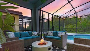 Un espace extérieur aménagé avec un foyer, des canapés confortables et une piscine.