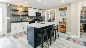 Cocina moderna con gabinetes blancos, una isla negra y un salpicadero gris.