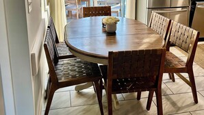 A kitchen with a dining table, chairs, a refrigerator, and a sliding glass door leading to a patio. - Charming 3-bedroom house in West Hyannisport (Barnstable)