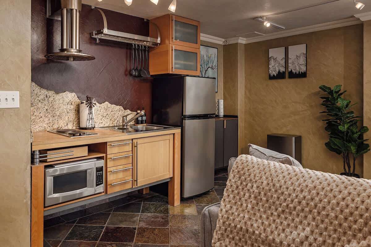 Cocina moderna con horno integrado, microondas y refrigerador de acero inoxidable.