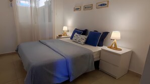 A bedroom with a bed, bedside tables, lamps, and wall art.