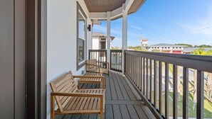 A wooden deck with three wooden chairs, a railing, and a view of a building in the background. - Vincente Seascape (A) (Panama City Beach)