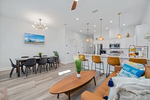 A modern kitchen with white cabinets, stainless steel appliances, and pendant lighting.
